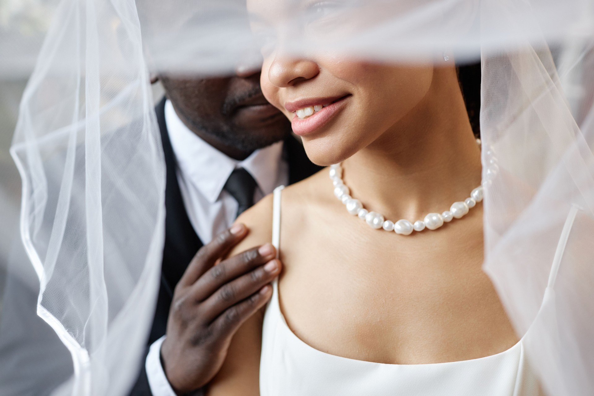 Closeup black couple as affectionate bride and groom embracing under veil